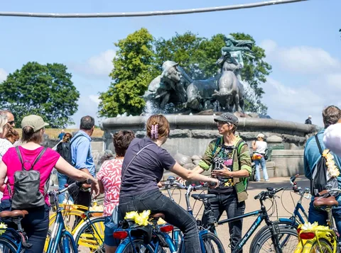 Groupe à vélo passant devant des maisons colorées sur le circuit incontournable de Copenhague