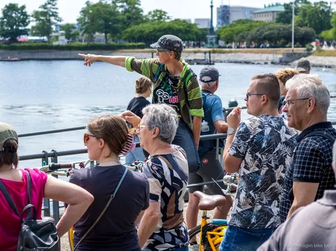 Guide local menant des cyclistes devant le palais d'Amalienborg lors d'un circuit à vélo à Copenhague