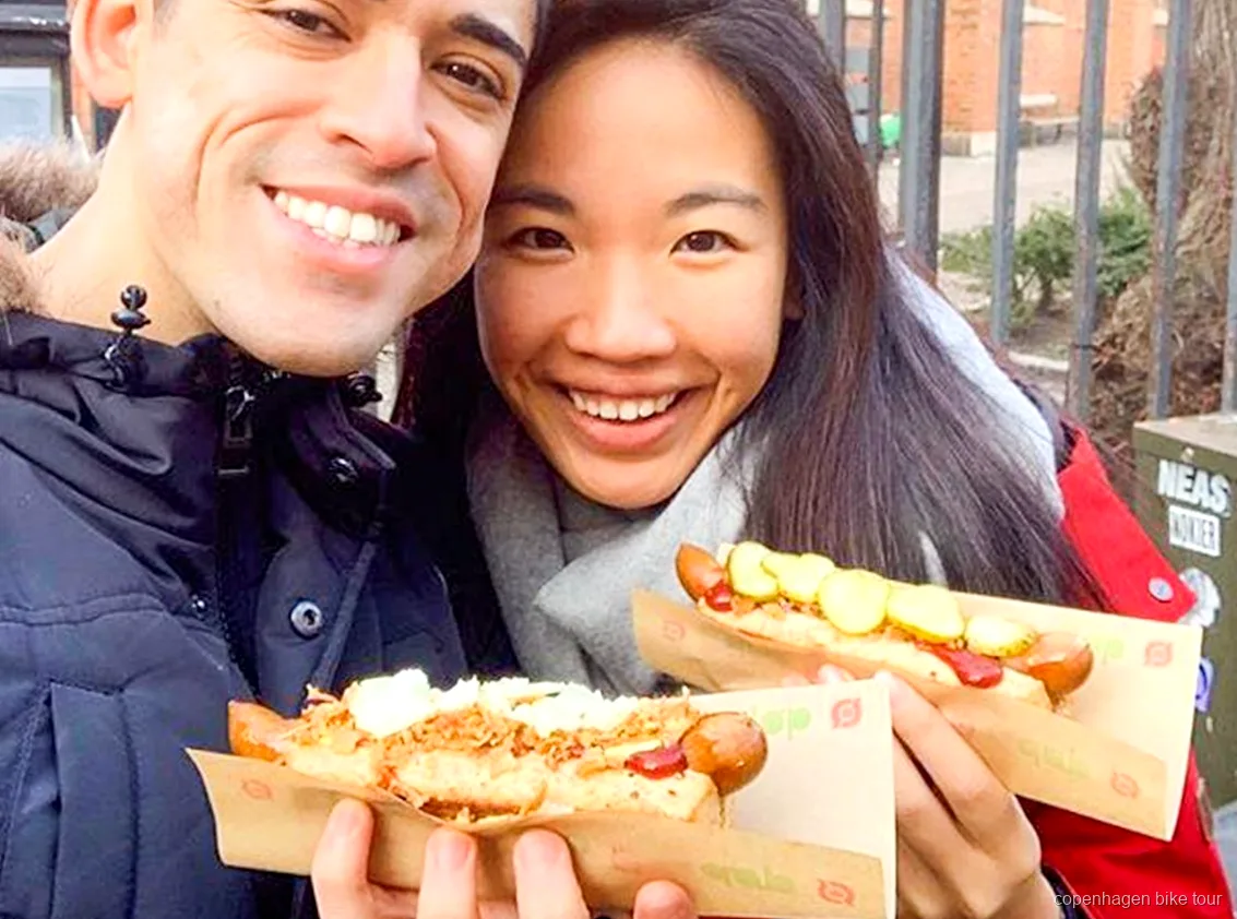 Guide distribuant une dégustation de hot-dog danois lors d'un circuit à vélo gourmand à Copenhague