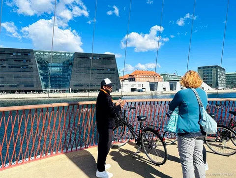 Guide explaining Christiania's history to a small cycling group in Copenhagen