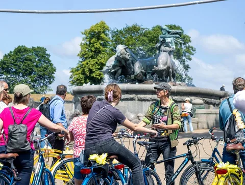 Group cycling past colorful canal houses on the Copenhagen highlights bike tour