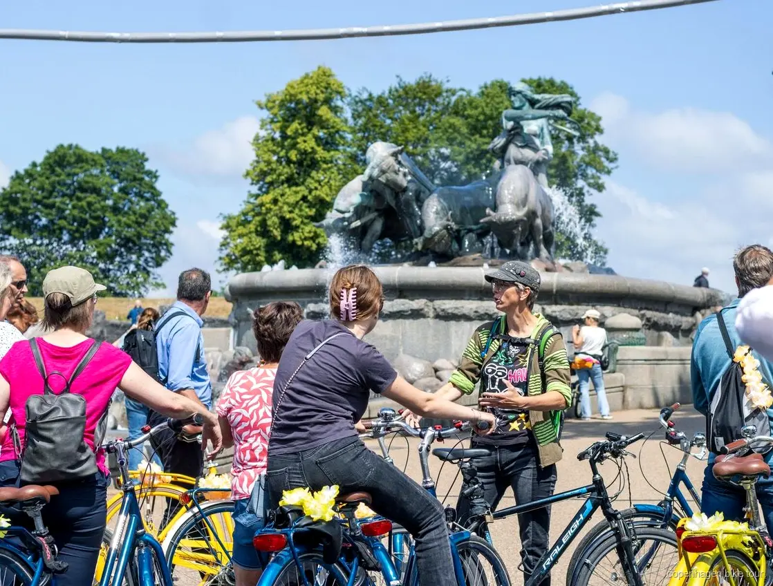 Group cycling past colorful canal houses on the Copenhagen highlights bike tour