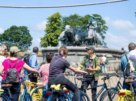 Gruppe der cykler forbi farverige kanalhuse på en cykeltur i København