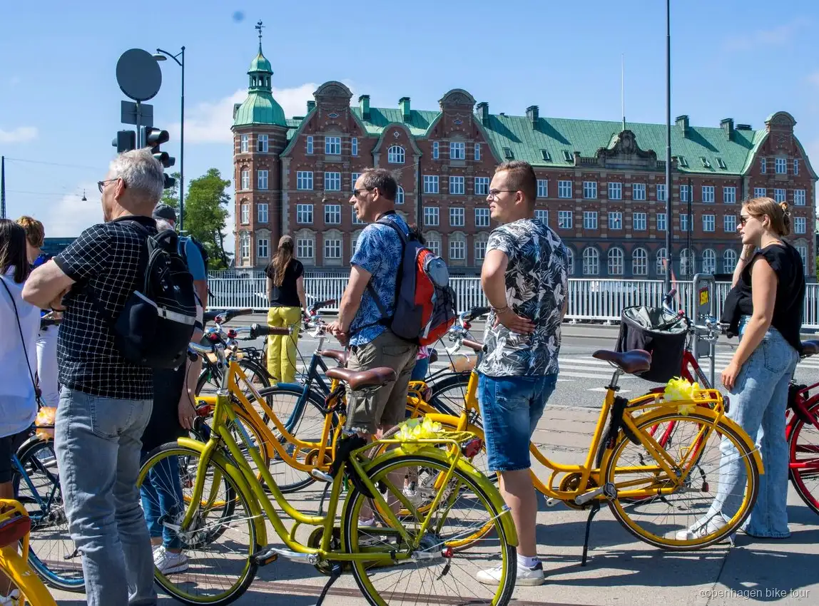 Ryttere der passerer Christiansborg Slot på en guidet cykeltur i København