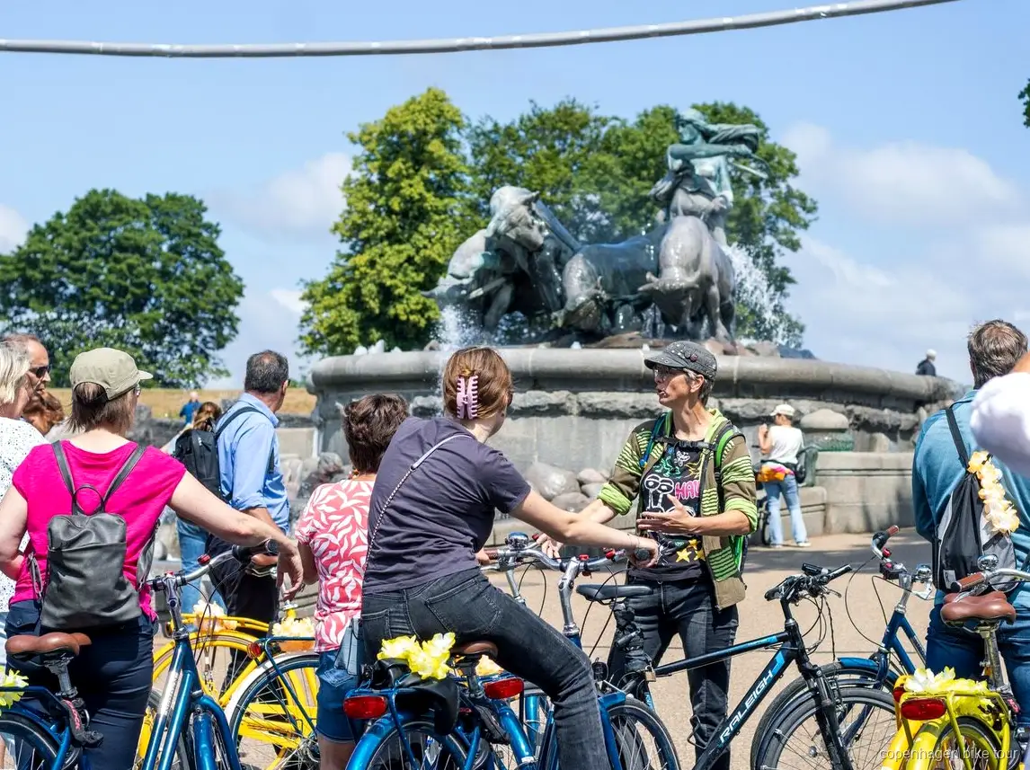 Grupp som cyklar förbi färgglada kanalhus på en cykeltur i Köpenhamn