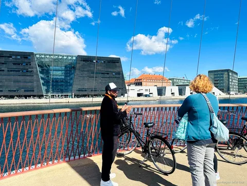Gids legt de geschiedenis van Christiania uit aan een kleine fietsgroep in Kopenhagen