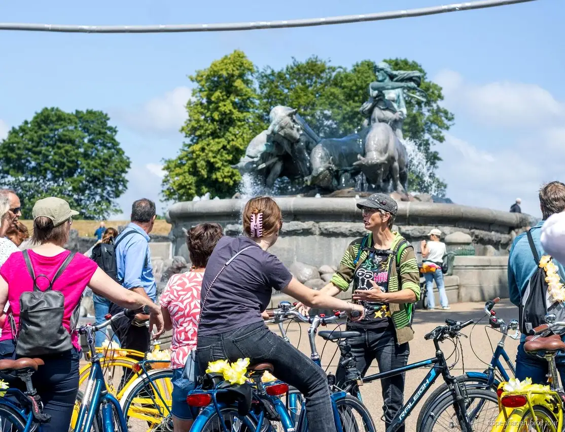 Groep die langs kleurrijke grachtenhuizen fietst op de fietstour Kopenhagen hoogtepunten