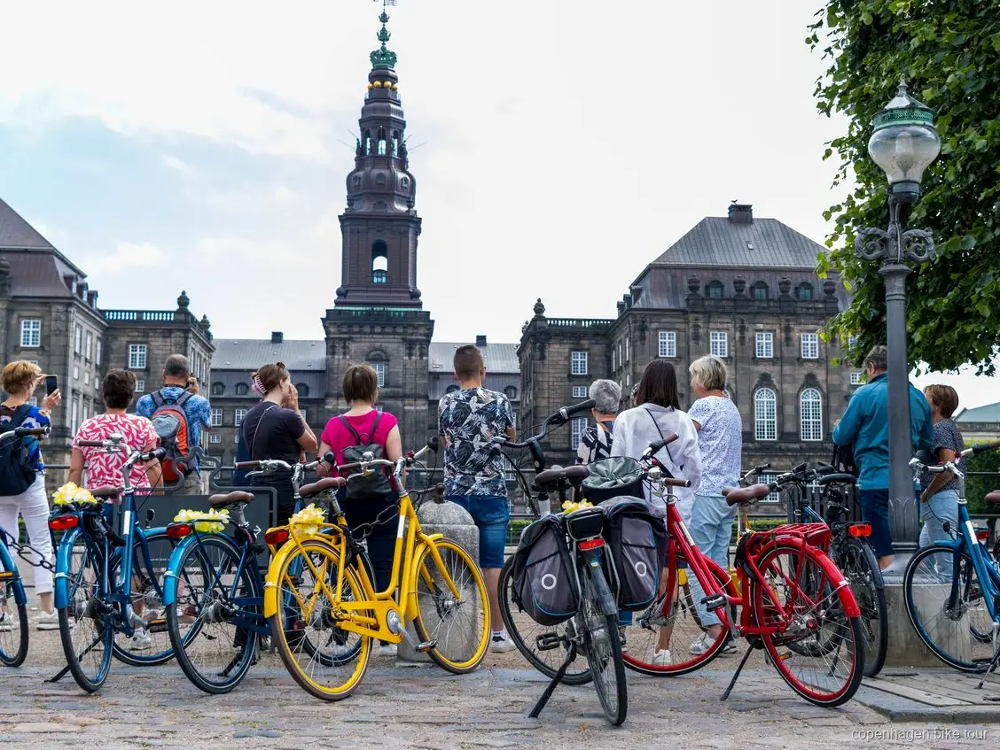 Fietsers gestopt bij het beeld van de Kleine Zeemeermin tijdens een begeleide fietstour in Kopenhagen