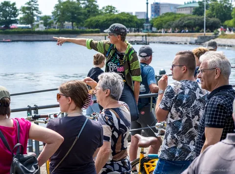 Guía local llevando a ciclistas junto al Palacio de Amalienborg en un tour en bici por Copenhague