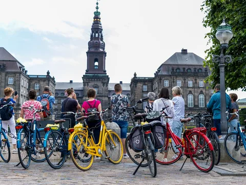 Ciclistas detenidos junto a la estatua de la Sirenita durante un tour guiado en bici por Copenhague