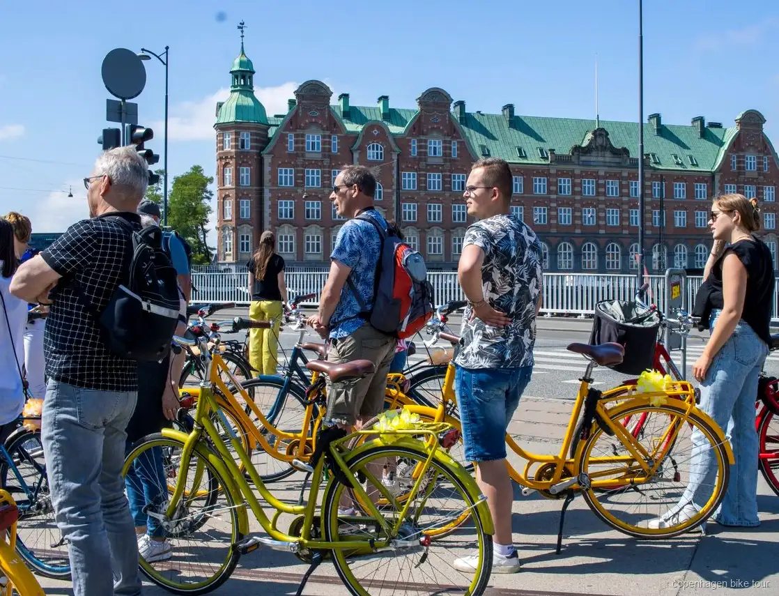 Ciclistas pasando por el Palacio de Christiansborg en un tour en bici guiado por Copenhague