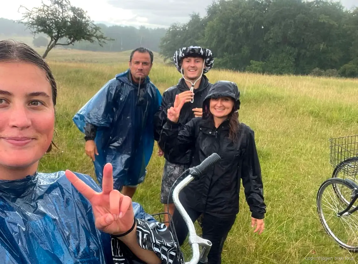 Ciervos salvajes pastando cerca de un grupo de ciclistas en Dyrehaven