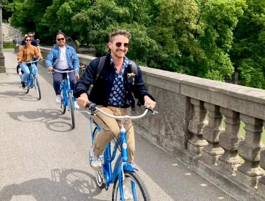 Ciclistas pasando por las casas de colores del canal de Nyhavn en un tour en bici corto por Copenhague