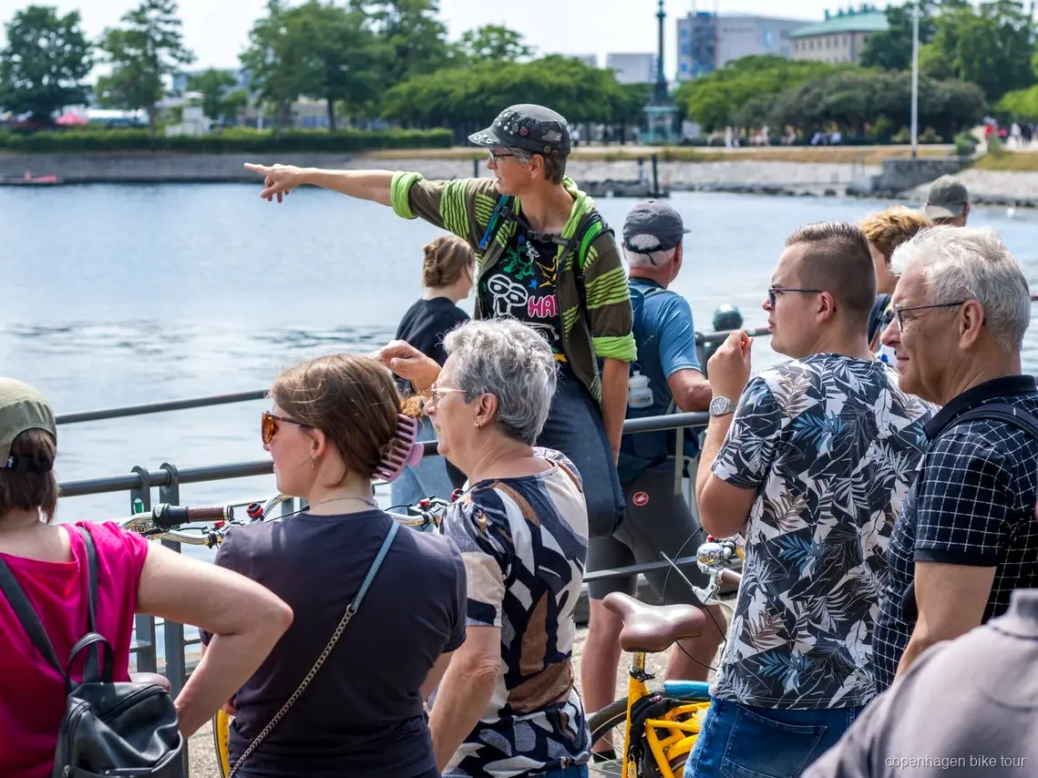 Guida locale che accompagna i ciclisti davanti al palazzo di Amalienborg durante un tour in bici a Copenaghen