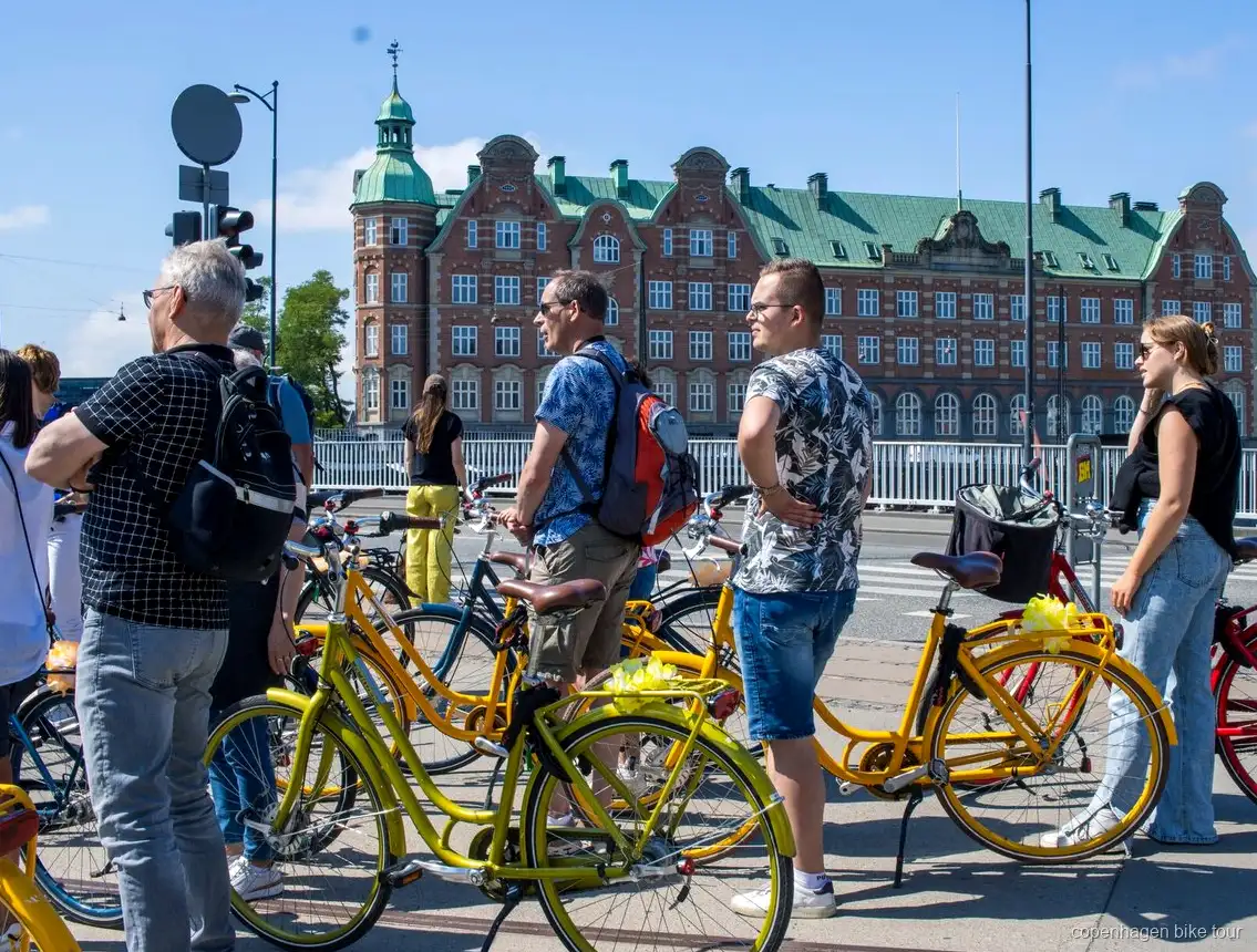 Ciclisti che passano davanti al palazzo di Christiansborg durante un tour in bici guidato a Copenaghen