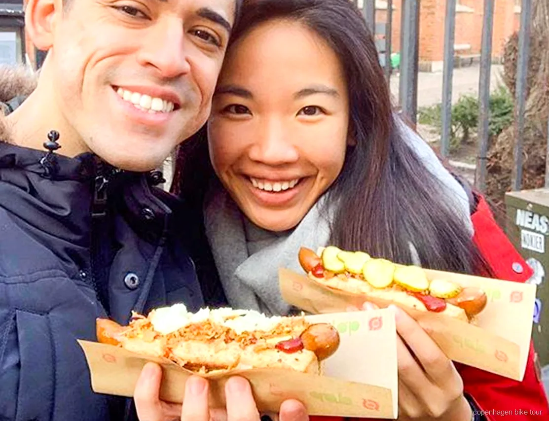 Guida che distribuisce un hot dog danese durante un tour in bici gastronomico a Copenaghen